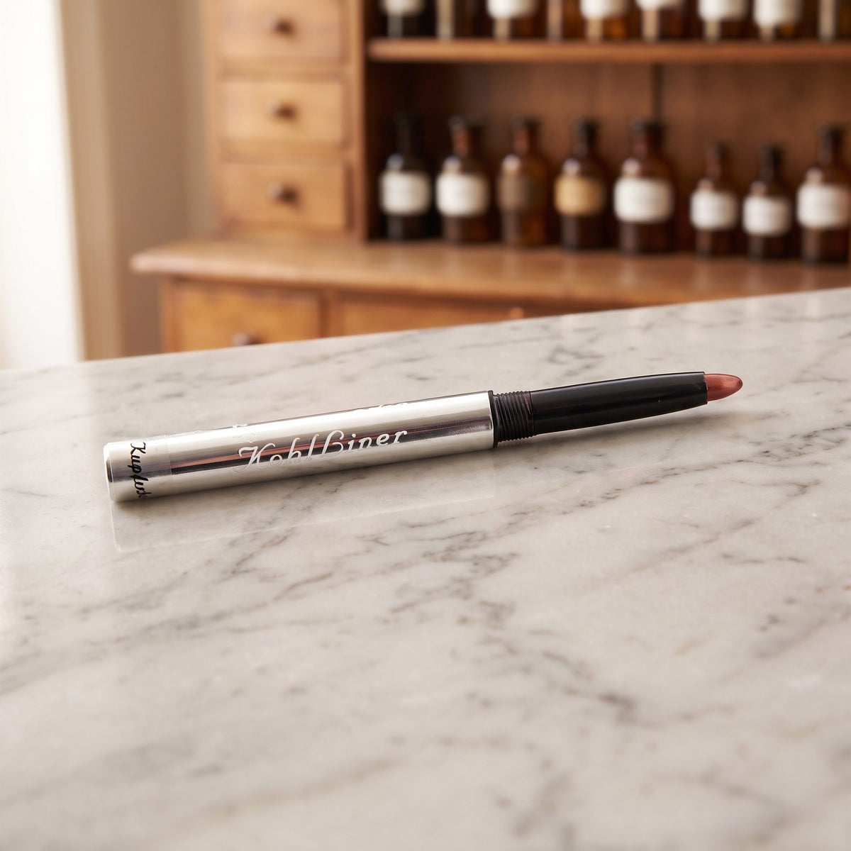 Kajal in Kupferbraun: silberner Drehstift mit kupferbrauner Mine auf Marmor