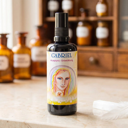 Seraphim Engel-Essenz Gabriel: Aura-Spray in dunkler Violettglasflasche auf Marmortheke vor Apothekerschrank, daneben ein Selenit und eine weiße Feder – Spirit of Gaia