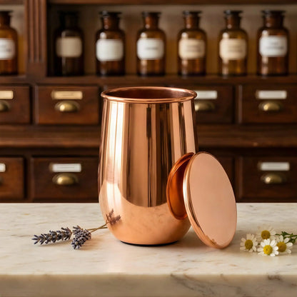 Polierter Kupferbecher mit angelehntem Deckel auf Marmortheke vor Apothekerschrank – Spirit of Gaia