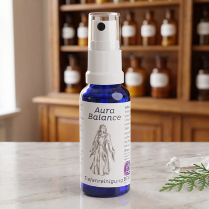 Energiespray Tiefenreinigung (Aura Balance): blaue Sprühflasche mit weißem Etikett auf Marmortheke vor Apothekerschrank, daneben ein Bergkristall und ein Zedernzweig – Spirit of Gaia