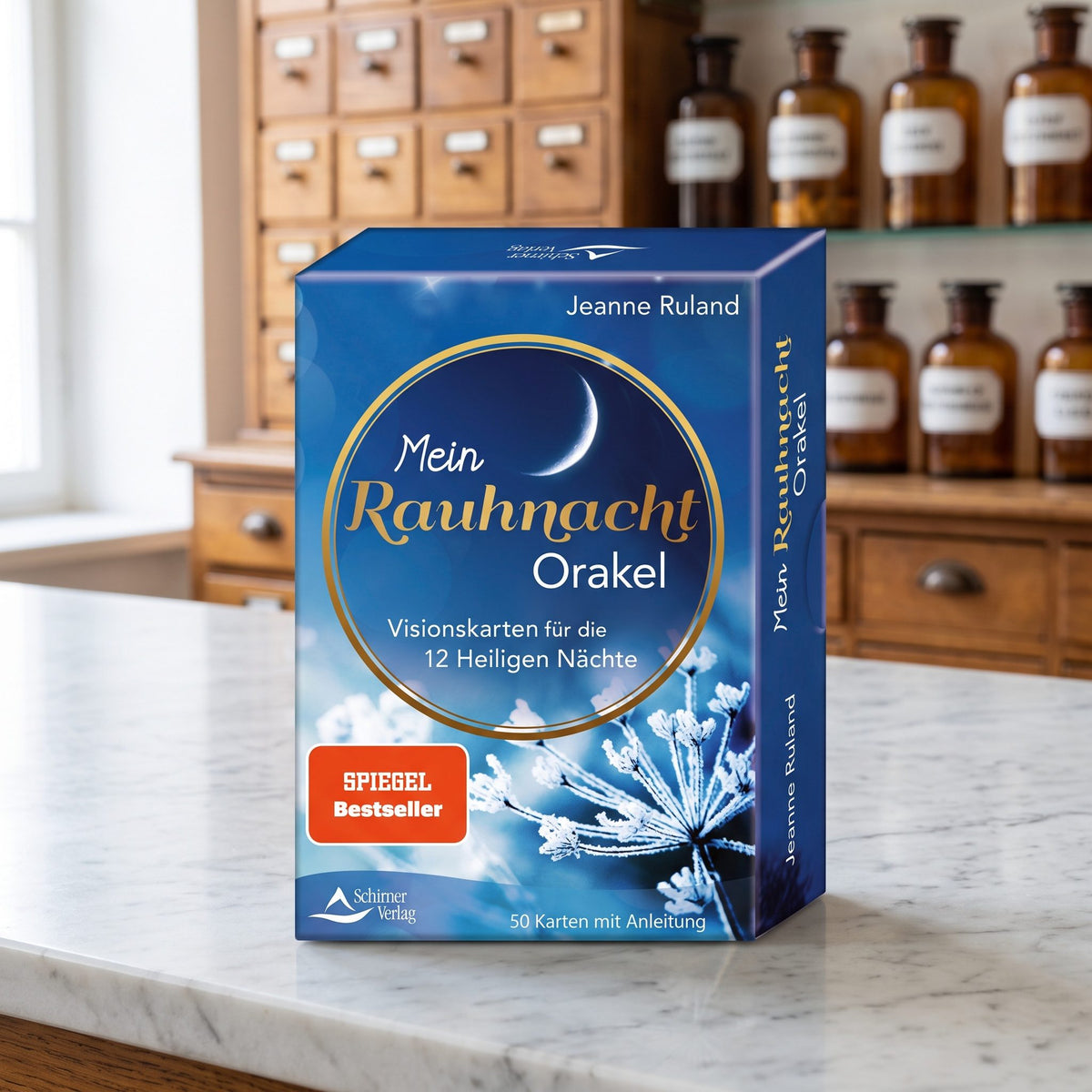 Kartenset Mein Rauhnacht-Orakel von Jeanne Ruland in blauer Schachtel steht auf der Marmortheke einer hellen Apotheke