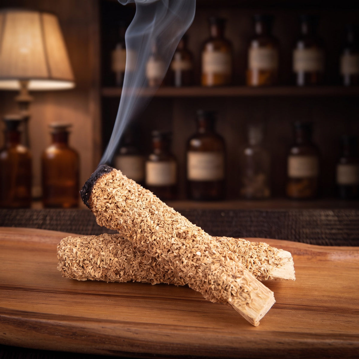 Ein Palo-Santo-Stab mit Eukalyptus glimmt an der geschwärzten Spitze, feiner Rauch steigt auf, der zweite Stab liegt daneben auf einer Holzschale