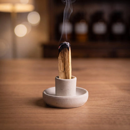 Ein Palo-Santo-Stab glimmt aufrecht im Tonhalter, feiner Rauch steigt auf