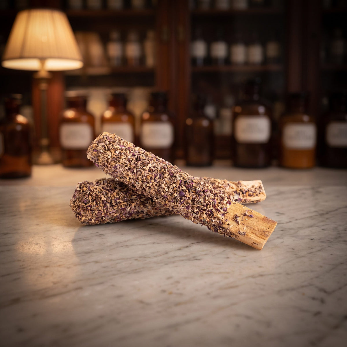 Palo Santo mit Lavendel von Berk: zwei mit Lavendelblüten überzogene Holzstäbe liegen gekreuzt auf der Marmortheke einer Apotheke am Abend