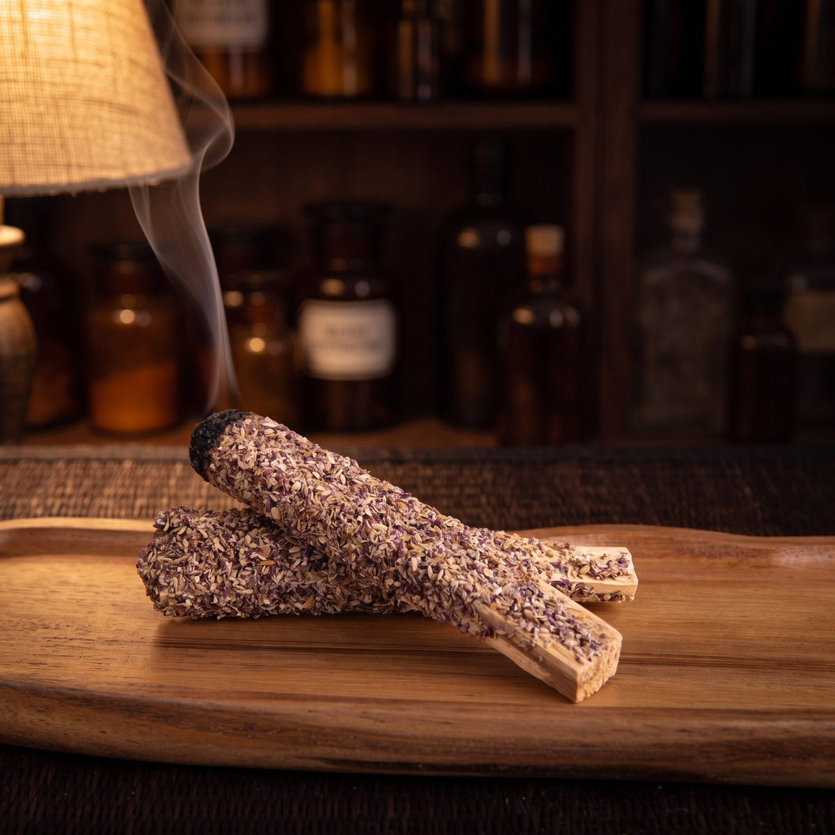 Ein Palo-Santo-Stab mit Lavendel glimmt an der geschwärzten Spitze, feiner Rauch steigt auf, der zweite Stab liegt daneben auf einer Holzschale