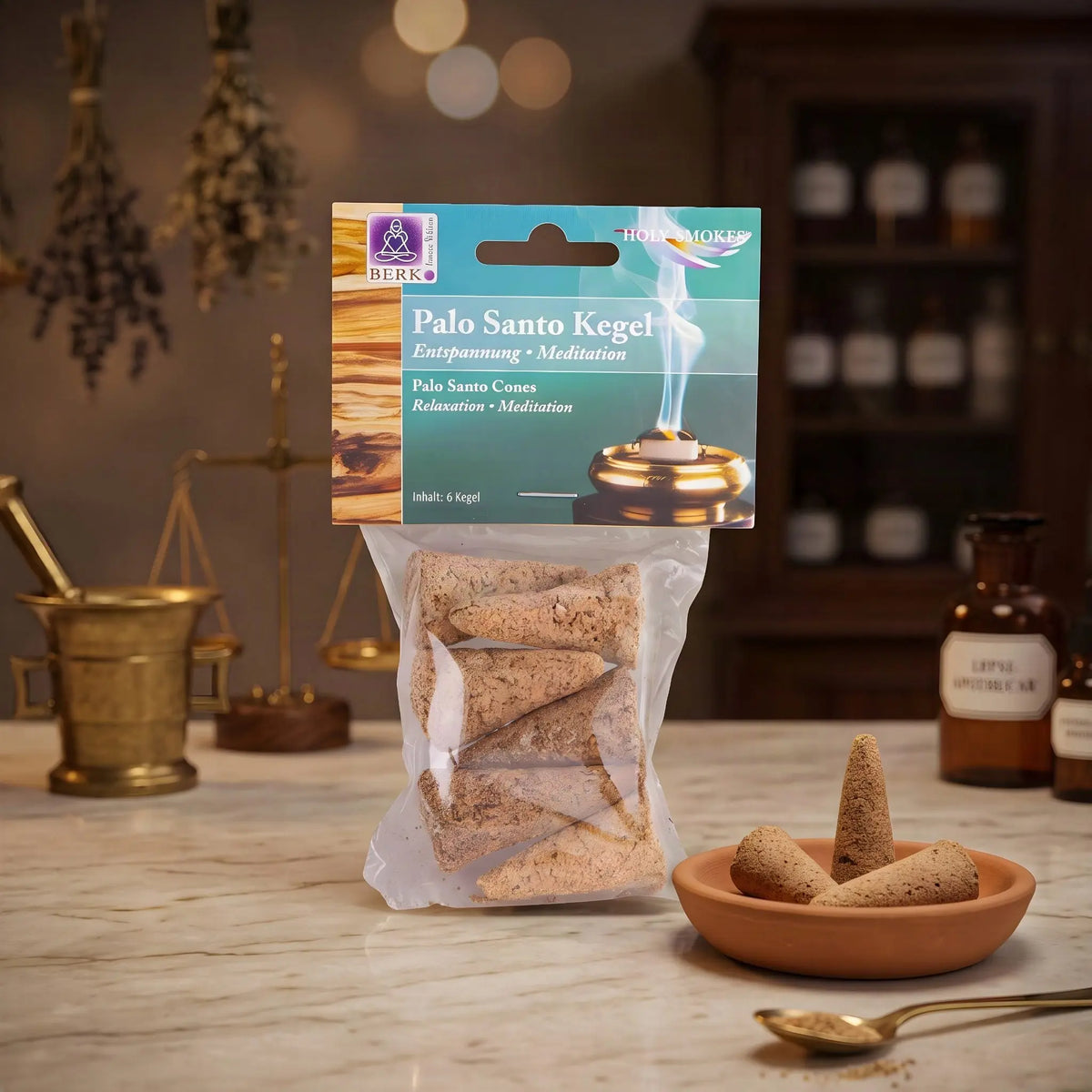 Palo Santo Räucherkegel von Berk: Tüte mit türkisgrünem Kartonkopf auf der Marmortheke einer Apotheke am Abend, daneben eine Terracottaschale mit Kegeln