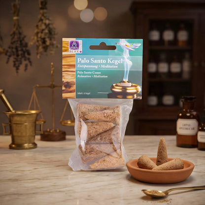 Palo Santo Räucherkegel von Berk: Tüte mit türkisgrünem Kartonkopf auf der Marmortheke einer Apotheke am Abend, daneben eine Terracottaschale mit Kegeln