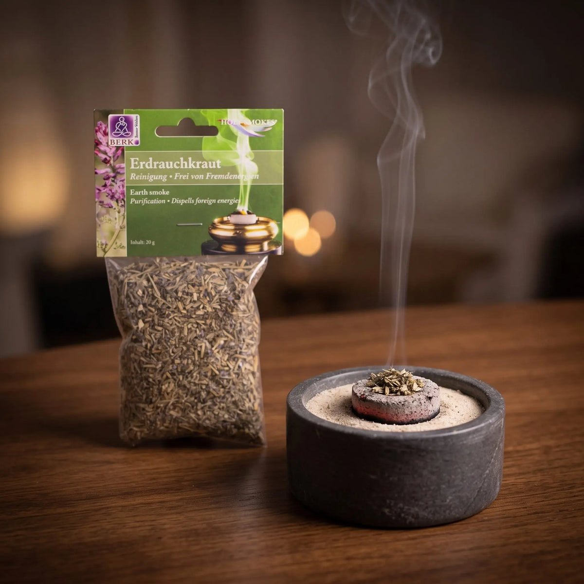Erdrauchkraut, sortenreines Räucherwerk von Berk, 20 g: eine Prise Erdrauchkraut glimmt auf der Räucherkohle, dahinter die Tüte, feiner Rauch steigt auf einer dunklen Holzplatte am Abend auf – Spirit of Gaia