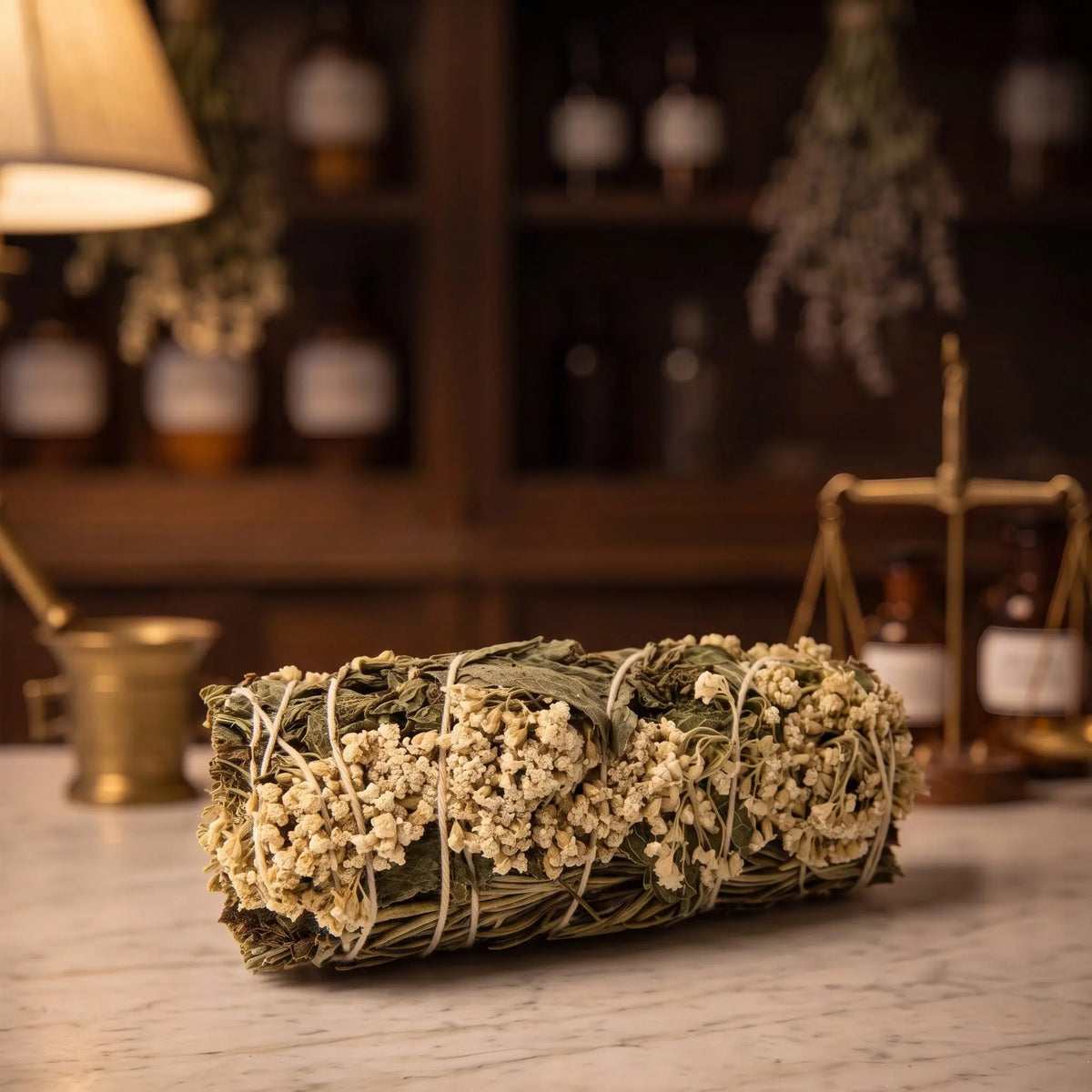 Premium-Räucherbündel Klarheit von Berk liegt auf der Marmortheke einer Apotheke am Abend, Schafgarbe, Rosmarin und Minze mit hellem Garn