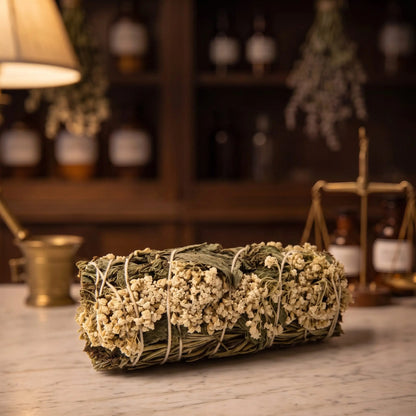Premium-Räucherbündel Klarheit von Berk liegt auf der Marmortheke einer Apotheke am Abend, Schafgarbe, Rosmarin und Minze mit hellem Garn