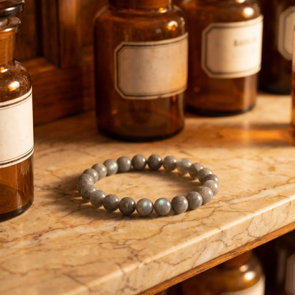 Labradorit Armband – graues Edelstein-Kugelarmband (8 mm) mit blau-grünem Schiller auf Marmorablage