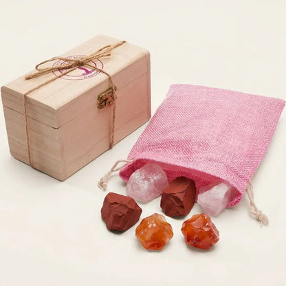 Wassersteine Liebe & Zuneigung – Holzkästchen mit pinkem Jutesäckchen und Rohsteinen Rosenquarz, Roter Jaspis und Karneol vor hellem Hintergrund – Spirit of Gaia