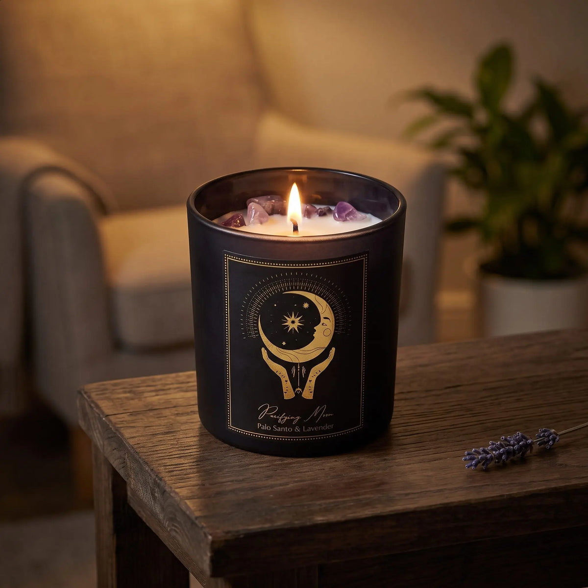 Manifestationskerze Purifying Moon mit Amethyst (Palo Santo & Lavendel): brennende Kerze im schwarzen Glas auf einem dunklen Holztisch im Wohnzimmer am Abend, daneben ein Lavendelzweig