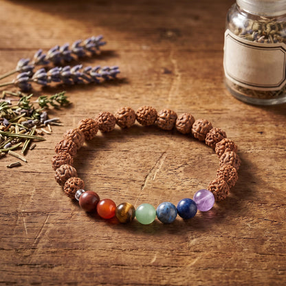Chakra Rudraksha Armband auf einem Holztisch neben Lavendel und einem Glas mit getrockneten Kräutern