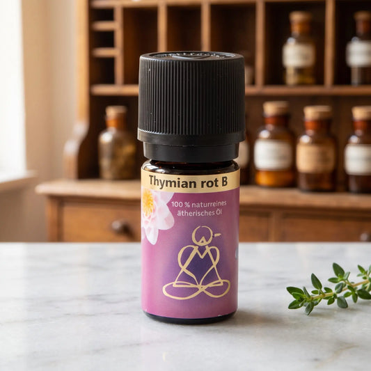 Ätherisches Öl Thymian rot: Fläschchen aus Braunglas auf Marmortheke vor Apothekerschrank, daneben ein Thymianzweig – Spirit of Gaia