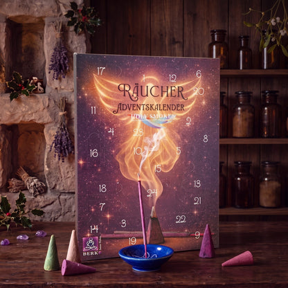 Der Kalender auf einem dunklen Holztisch, davor bunte Räucherkegel und eine blaue Keramikschale mit glimmendem Räucherstäbchen