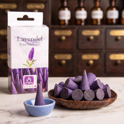 Lieferumfang der Lavendelblüten Räucherkegel von Berk: violette Kegel in einer Holzschale, ein Kegel im beiliegenden blauen Keramikschälchen, dahinter die Packung