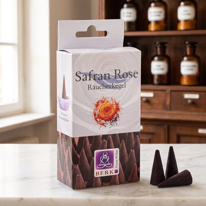 Safran Rose Räucherkegel von Berk: Packung auf einer Marmortheke vor einem Apothekerschrank, daneben drei lose dunkelbraune Räucherkegel – Spirit of Gaia