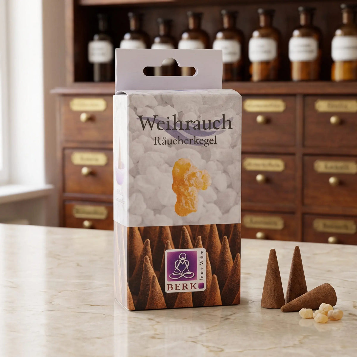 Weihrauch Räucherkegel von Berk: Packung auf einer Marmortheke vor einem Apothekerschrank, daneben drei lose Räucherkegel und weiße Weihrauchkörner – Spirit of Gaia