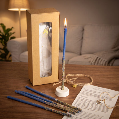 Das Set Licht der Wahrheit auf einem dunklen Holztisch im Wohnzimmer am Abend, eine Kerze brennt im Ständer, vier weitere liegen davor, dazu die Anleitung und das Amulett
