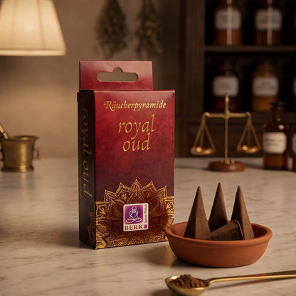 Royal Oud Räucherpyramiden von Berk: rote Schachtel mit Goldschrift auf der Marmortheke einer Apotheke am Abend, daneben eine Schale mit Kegeln