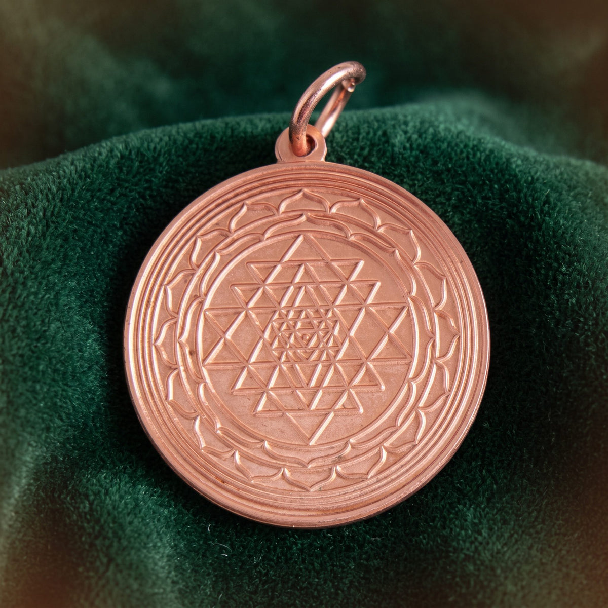 Shri Yantra aus Kupfer, Anhänger mit Öse, liegt auf dunkelgrünem Samt