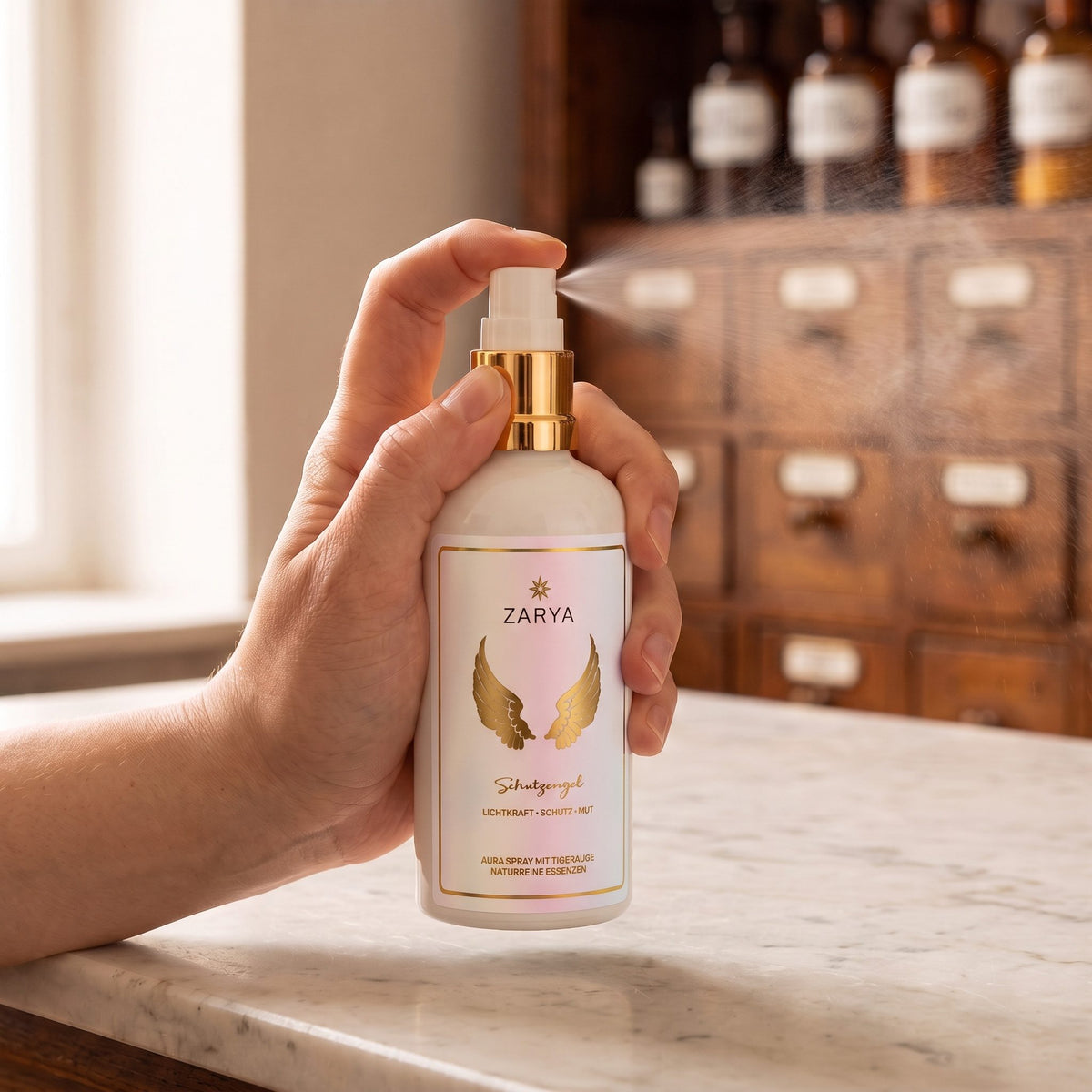 Eine Hand sprüht das Aura Spray Schutzengel fein in den Raum