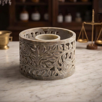 Smudge Bowl Yara groß von Berk: Schale aus Speckstein mit geschnitzten Rosenranken auf der Marmortheke einer Apotheke am Abend