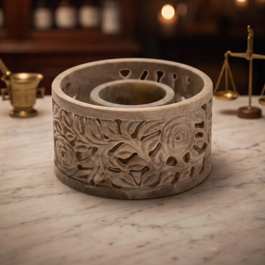 Smudge Bowl Yara klein von Berk: runde Schale aus Speckstein mit geschnitzten Rosenranken auf der Marmortheke einer Apotheke am Abend