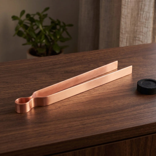 Räucherzange aus Kupfer auf einem dunklen Holz-Sideboard im Wohnzimmer