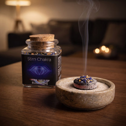 Stirnchakra, Chakra-Räuchermischung von Berk, 50 ml im Korkglas: glimmende Räucherkohle mit einer Prise der blauen Kornblumenmischung in einer Specksteinschale, dahinter das Korkglas, feiner Rauch steigt auf einer dunklen Holzplatte am Abend auf – Spirit of Gaia