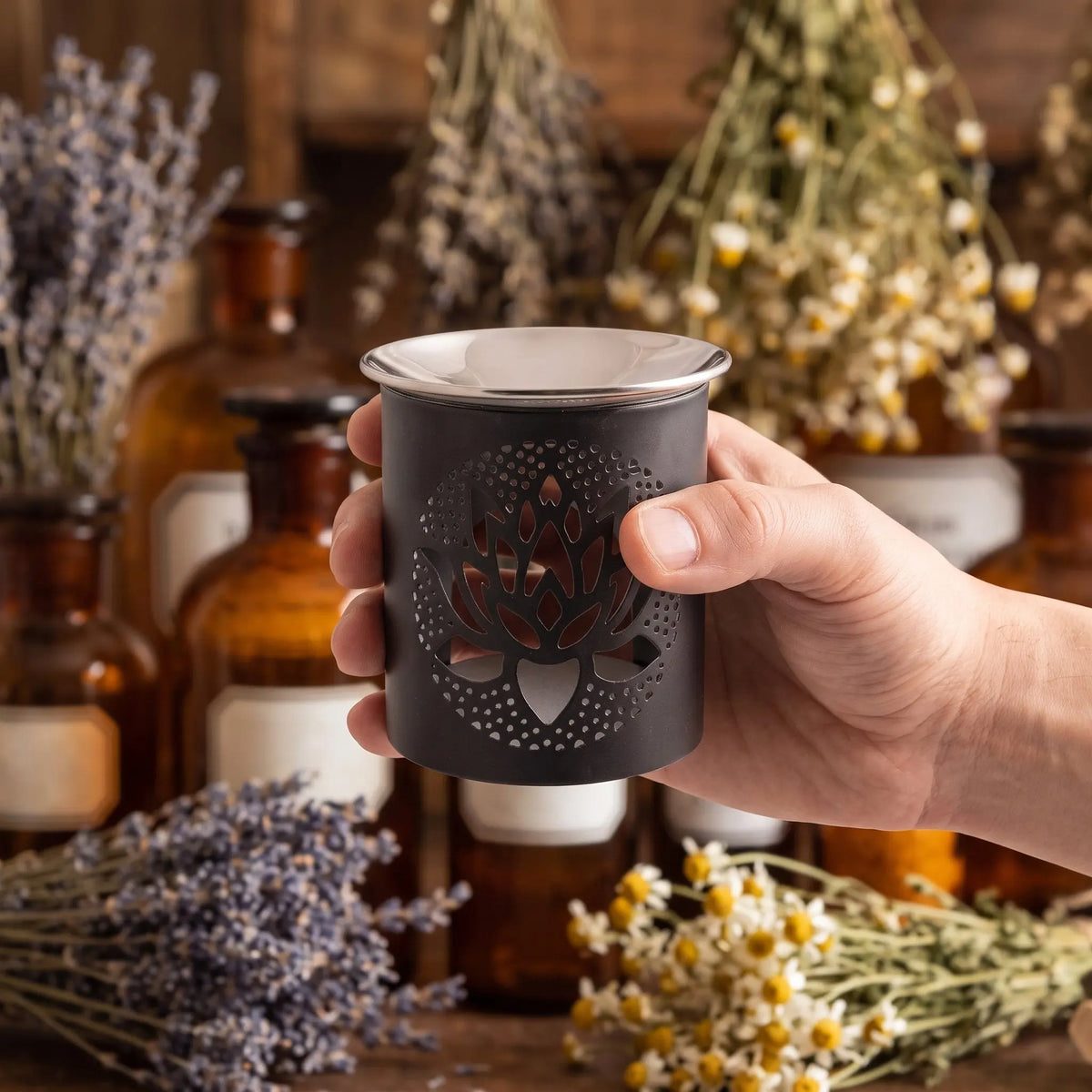 Schwarzes Räuchergefäß aus Eisen mit ausgestanztem Lotus und flacher Edelstahlschale – Groessenvergleich in der Hand