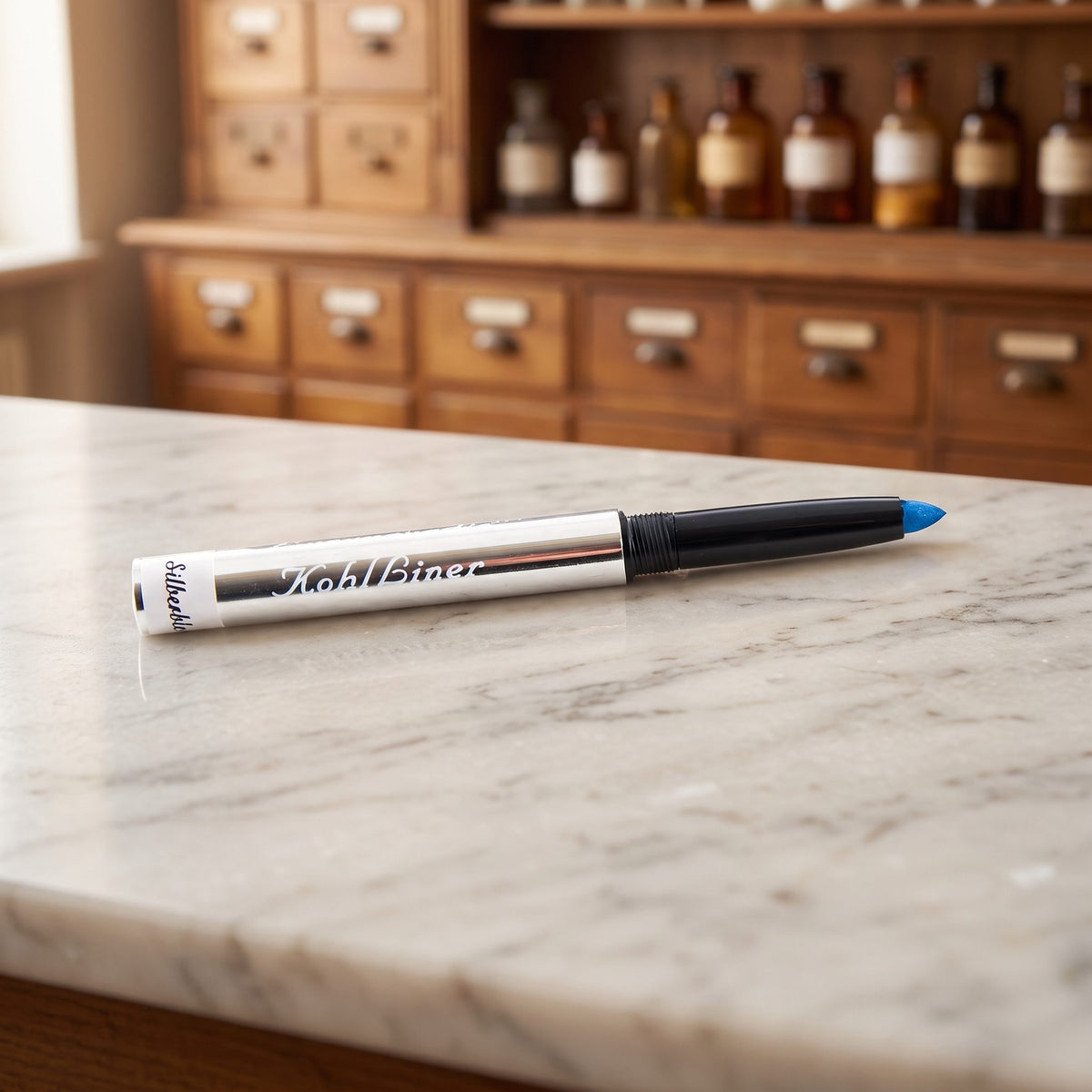 Kajal in Silberblau: silberner Drehstift mit azurblauer Mine auf Marmor