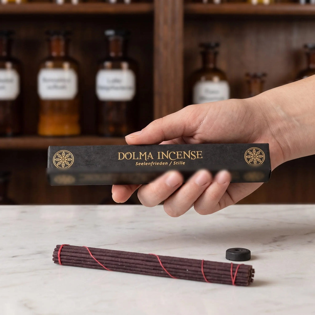 Größenvergleich: eine Hand hält die längliche Schachtel der tibetischen Räucherstäbchen Dolma Incense von Berk