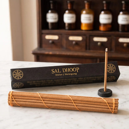 Tibetische Räucherstäbchen Sal Dhoop von Berk: schwarze Schachtel mit Goldschrift auf einer Marmortheke vor einem Apothekerschrank, davor das Stäbchenbündel und der Tonhalter