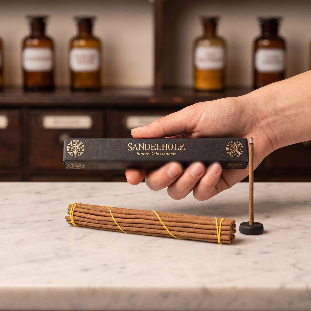 Größenvergleich: eine Hand hält die längliche Schachtel der tibetischen Räucherstäbchen Sandelholz von Berk