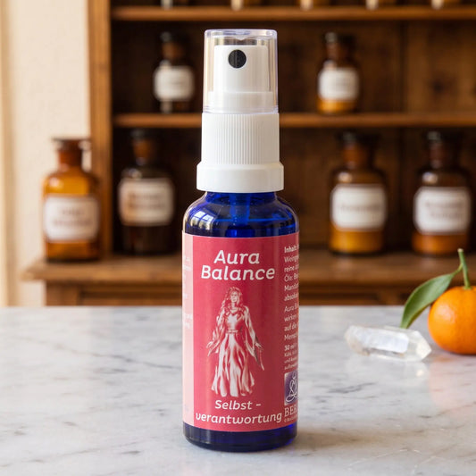 Energiespray Selbstverantwortung (Aura Balance): blaue Sprühflasche mit rotem Etikett auf Marmortheke vor Apothekerschrank, daneben ein Bergkristall und eine Mandarine – Spirit of Gaia