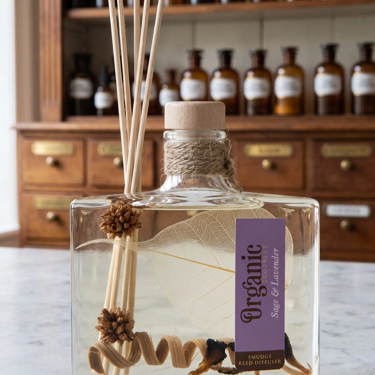 Flaschenhals des Reed Diffusers Salbei und Lavendel aus der Nähe: Holzstopfen, Jutekordel, Schilfrohrstäbchen und das Blattskelett im Öl