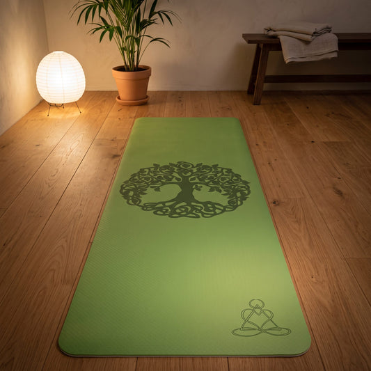 EcoBalance Yogamatte aus TPE, 182 × 61 cm, 6 mm, Baum des Lebens, hellgrün/grau: ausgerollt auf dem Holzboden, in der Mitte der geprägte Baum des Lebens, warmes Abendlicht – Spirit of Gaia