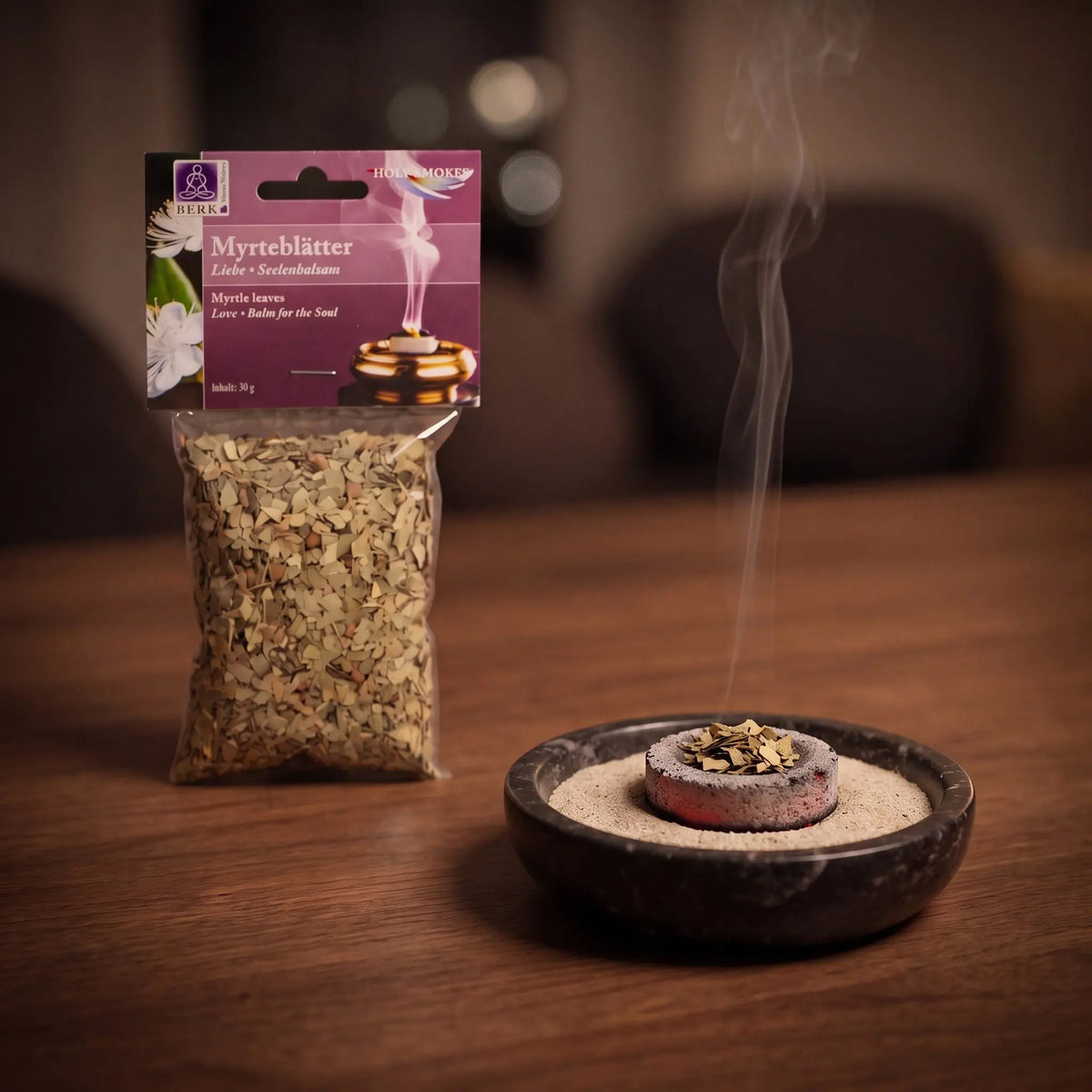 Myrteblätter, sortenreines Räucherwerk von Berk, 30 g: eine Prise Myrteblätter glimmt auf der Räucherkohle, dahinter die Tüte, feiner Rauch steigt auf einer dunklen Holzplatte am Abend auf – Spirit of Gaia