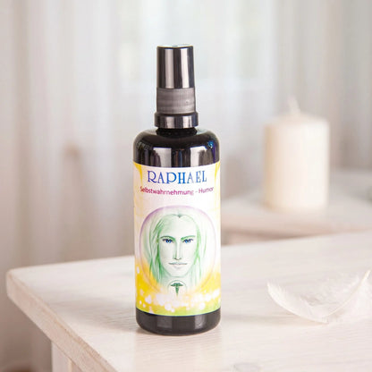 Seraphim Engel-Essenz Raphael: Sprühflasche auf einem weißen Beistelltisch in einem hellen Raum, daneben eine weiße Feder