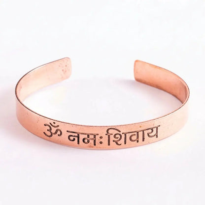 Kupferarmreif mit Om-Namah-Shivaya-Mantra freigestellt vor weißem Hintergrund