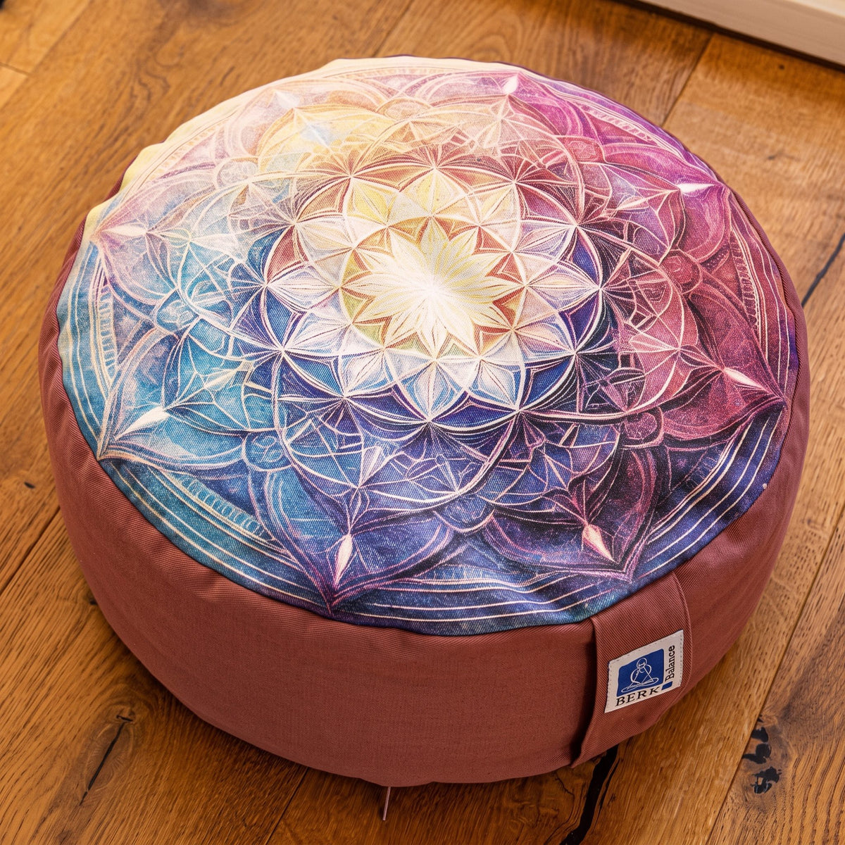 Nahaufnahme der Oberseite des Meditationskissens Mandala in Altrosa: Lotusstern in der Mitte, Ringe aus feinen Linien und spitzen Blütenblättern im Farbverlauf, Tragelasche mit Berk-Balance-Etikett