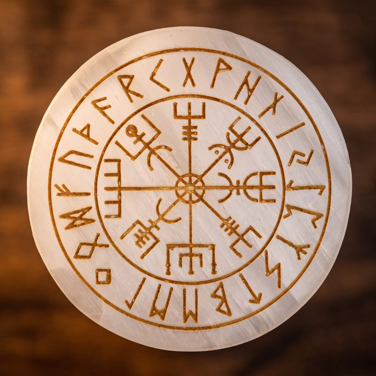 Nahaufnahme der Vegvisir-Gravur auf der Selenitplatte: acht Arme und Runenring in Goldbraun