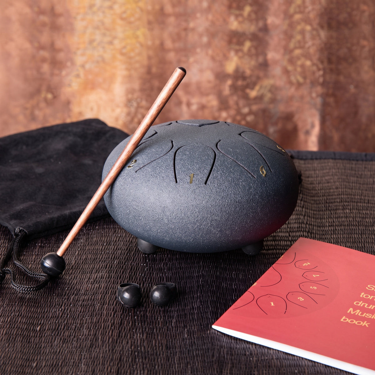 Die mittlere dunkelblaue Steeldrum mit Klangstab, Fingerkuppen, Liederbuch und Tasche