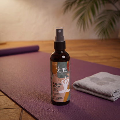 Das Yogamatten-Spray Prana Flow steht auf einer ausgerollten lila Yogamatte, daneben ein zusammengelegtes graues Tuch, vor der Flasche feine Wassertropfen