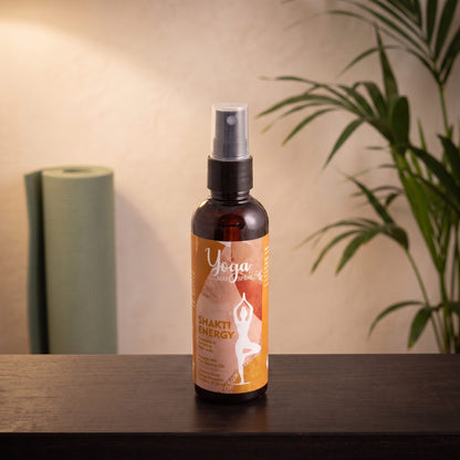Yogamatten-Spray Shakti Energy von Song of India, 100 ml, auf einer dunklen Holzbank in einem Meditationsraum, dahinter eine aufgerollte Yogamatte