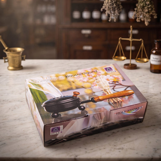 Set Energetische Hausreinigung von Berk: die Geschenkbox mit Räucherpfanne und Salbeibündel auf der Marmortheke einer alten Apotheke am Abend – Spirit of Gaia