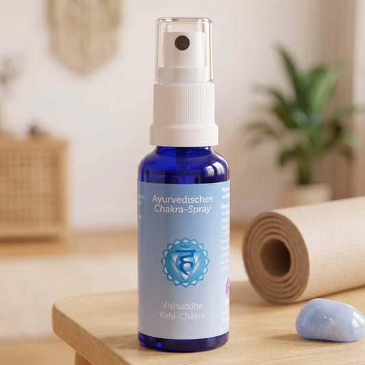 Ayurvedisches Chakra-Spray Vishuddha (Kehl-Chakra): 30-ml-Sprühflasche auf einem Holzhocker neben einer gerollten Yogamatte, daneben blauer Chalcedon