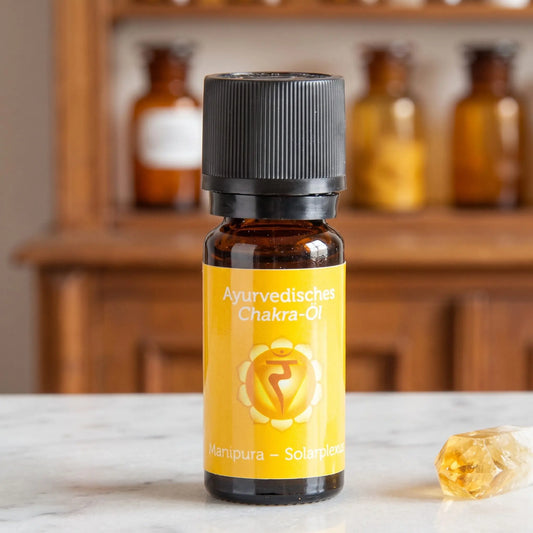 Ayurvedisches Chakra-Öl Manipura (Solarplexus-Chakra): 10-ml-Fläschchen aus Braunglas auf Marmortheke vor Apothekerschrank, daneben Citrin – Spirit of Gaia